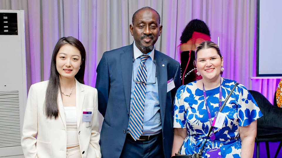 Global Alumni Ambassador Hakeem is standing with Jing who is the Engagement Officer along with Darcy Hodges, Supporter Relations Manager at the University. They are at the alumni in Lagos and are standing together smiling.